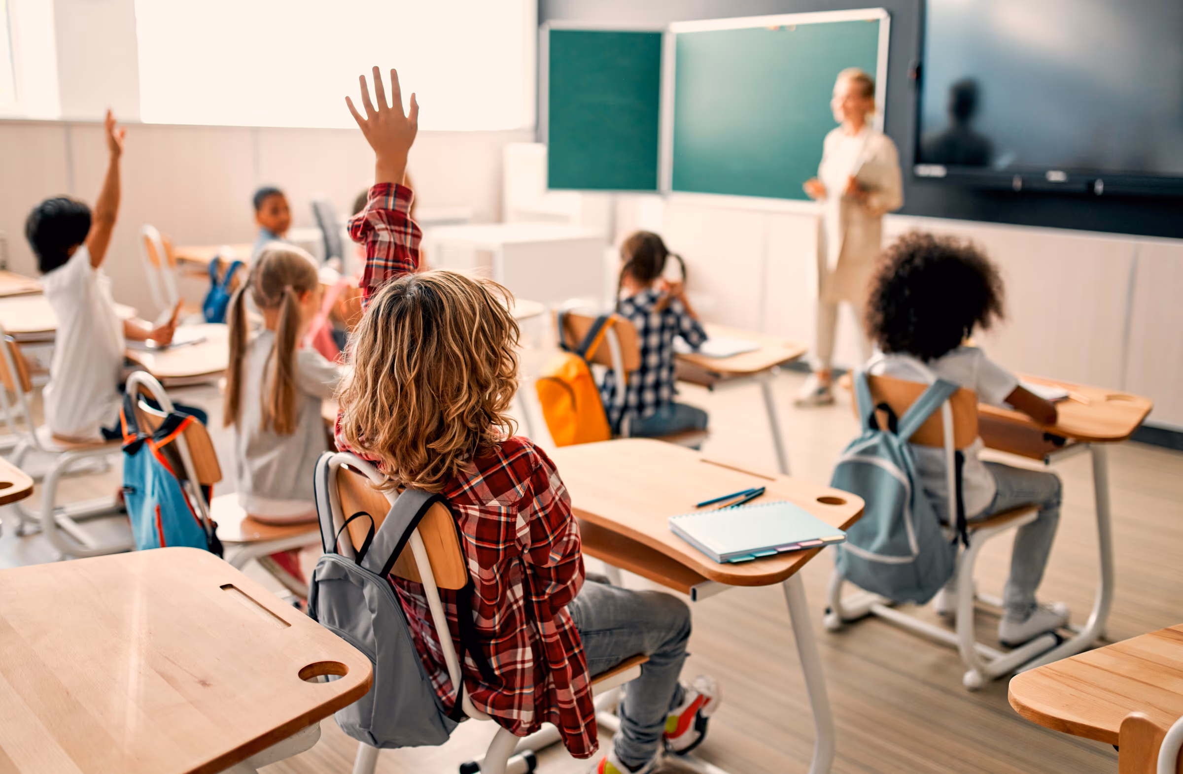 Students with hands raised in a classroom