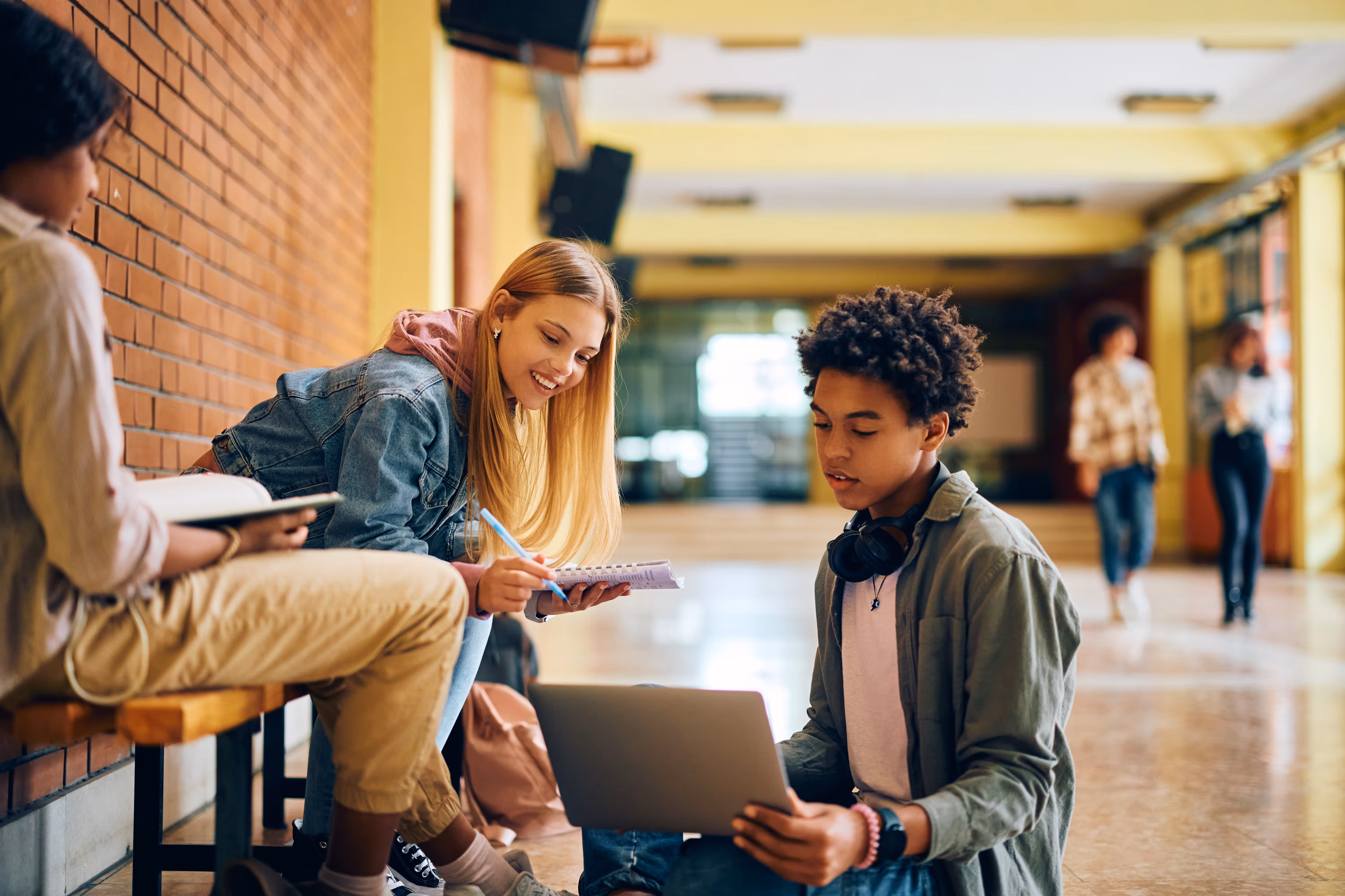 Teens with laptops in a school corridor